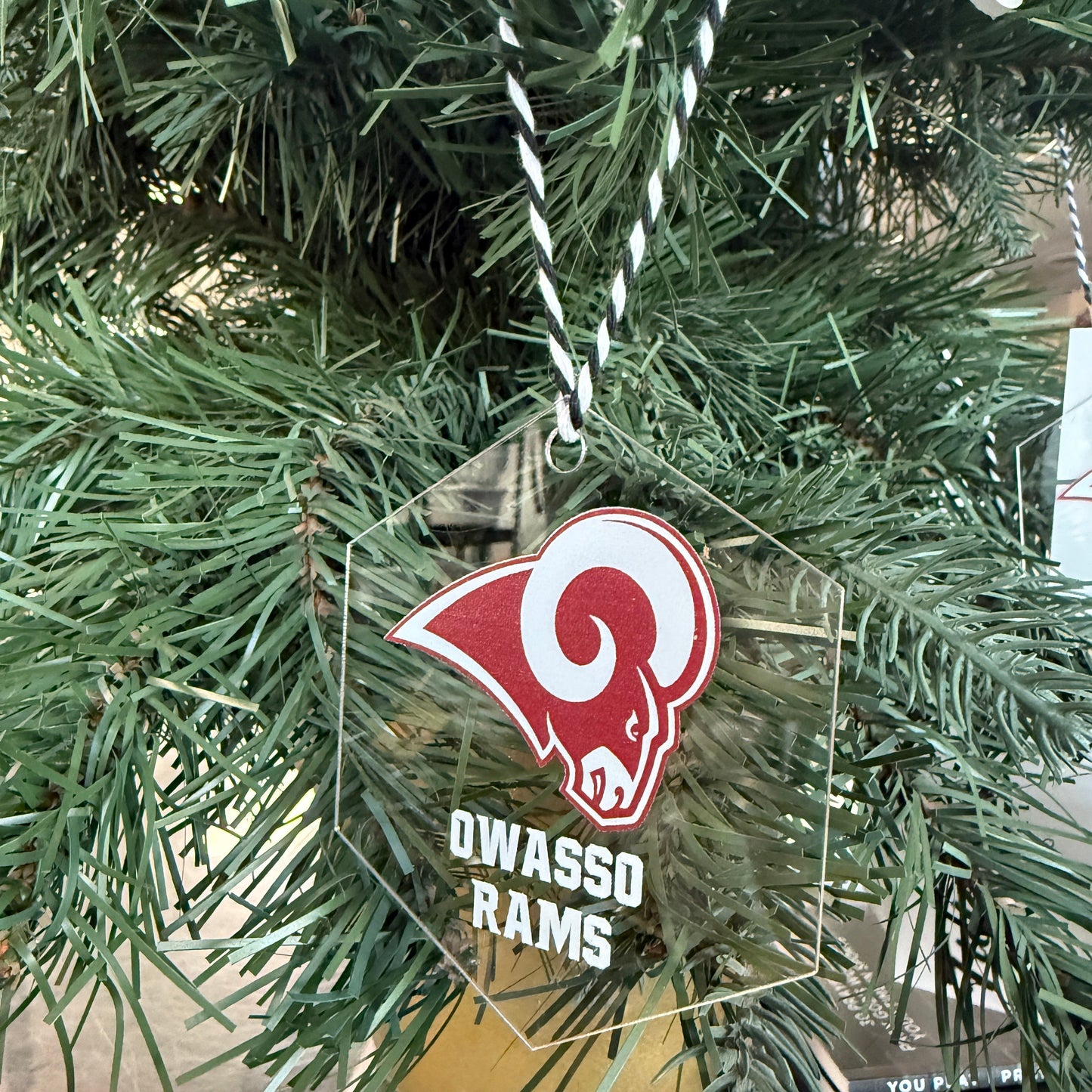 Acrylic ornament with a logo and text hanging on a Christmas tree